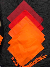 A traditional Indian patka (scarf) with a red, orange, and black color scheme, displayed on a dark background.